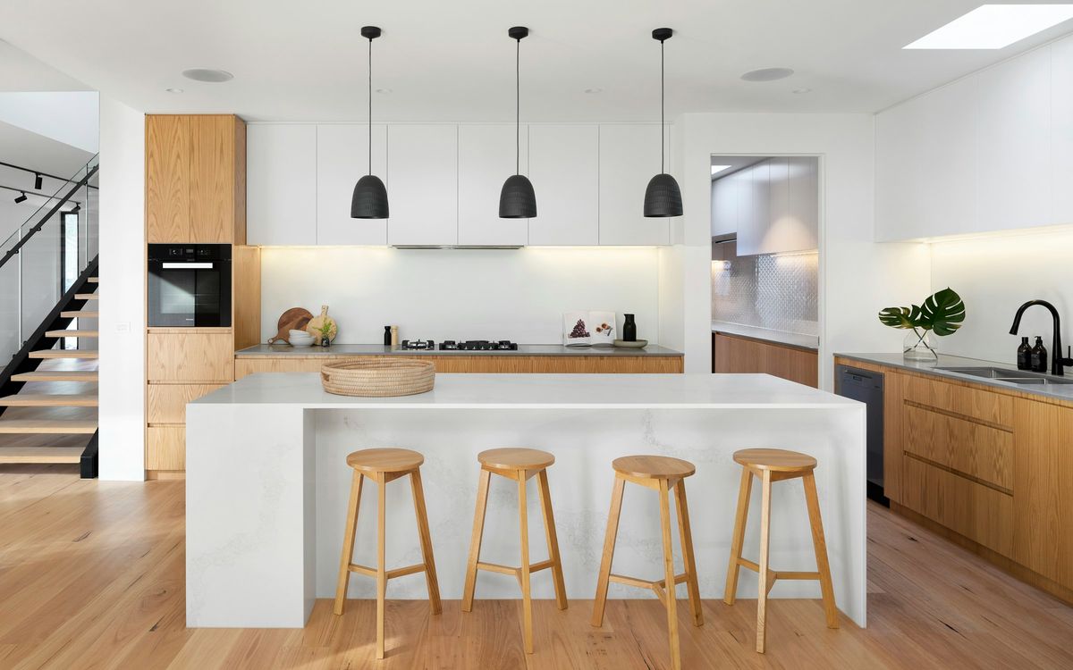 Cocina reformada en una vivienda de Mallorca, con isla, madera natural y encimera clara