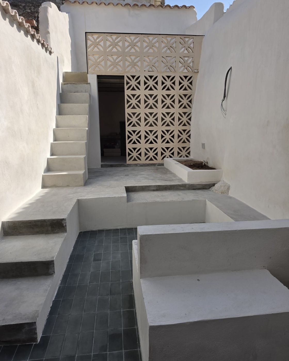 Escalera de hormigón y celosía cerámica en el patio de una vivienda reformada en Sineu
