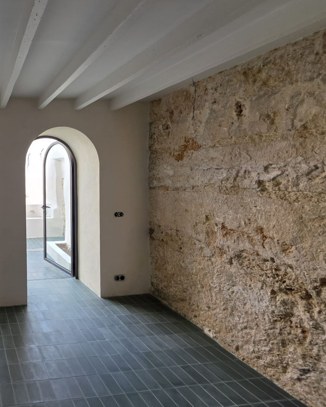 Pared de marés recuperada y vigas pintadas en el interior de una casa reformada en Sineu
